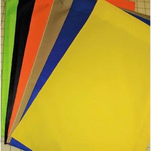 May include: A stack of fabric swatches in various colors, including black, orange, tan, blue, green, and yellow. The swatches are arranged in a fan shape, with the yellow swatch on top.