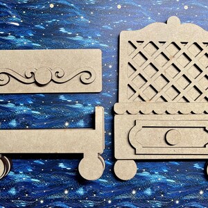 May include: Unfinished wooden dollhouse furniture set, including a bed frame, a dresser with a lattice back, and a decorative wall piece. The pieces are light brown and sit on a blue background.