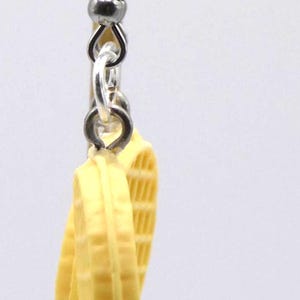 May include: A pair of novelty earrings with a waffle design. The earrings are light yellow and have a silver-coloured hook. The waffle earrings are a fun and unique accessory.