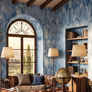 May include: A room featuring blue and white chevron wallpaper, a brown leather sofa, and a wooden desk. The desk holds a globe, books, and a white vase with flowers. A stone fireplace, arched window, and built-in bookshelves are visible.