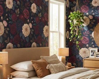 May include: A bedroom featuring a beige upholstered bed with white and tan bedding, a light wood dresser, two matching nightstands with lamps, a round woven mirror, a hanging plant, and dark floral wallpaper with red and cream flowers.