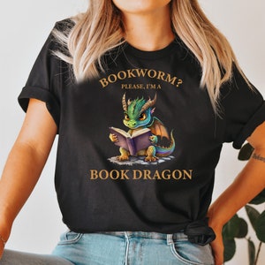 May include: Black t-shirt with a green dragon reading a book. The text on the shirt reads "Bookworm? Please, I'm a Book Dragon."