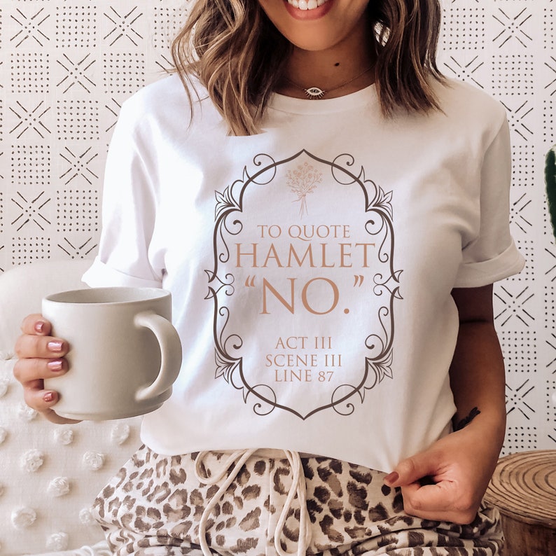 May include: White t-shirt with a brown graphic that says "To quote Hamlet "NO." Act III Scene III Line 87"