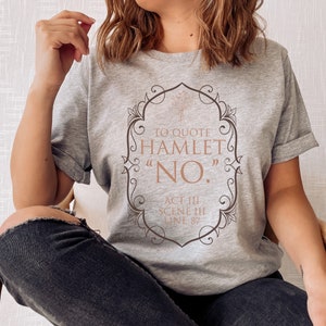 May include: Gray t-shirt with a graphic design featuring a quote from Hamlet: "To quote Hamlet "No." Act III Scene III Line 87"