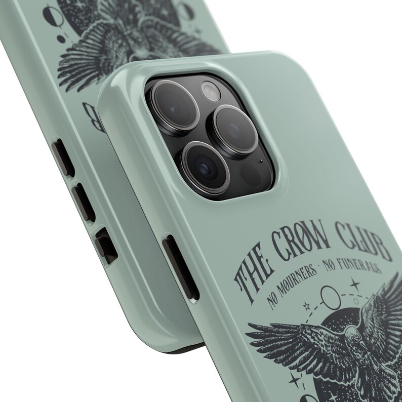 May include: A sage green phone case with a black and white illustration of a crow with the text "The Crow Club No Mourners No Funerals".