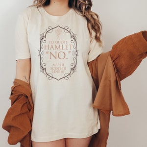 May include: A white t-shirt with a brown ornate frame and the text "To quote Hamlet "NO." Act III Scene III Line 87".