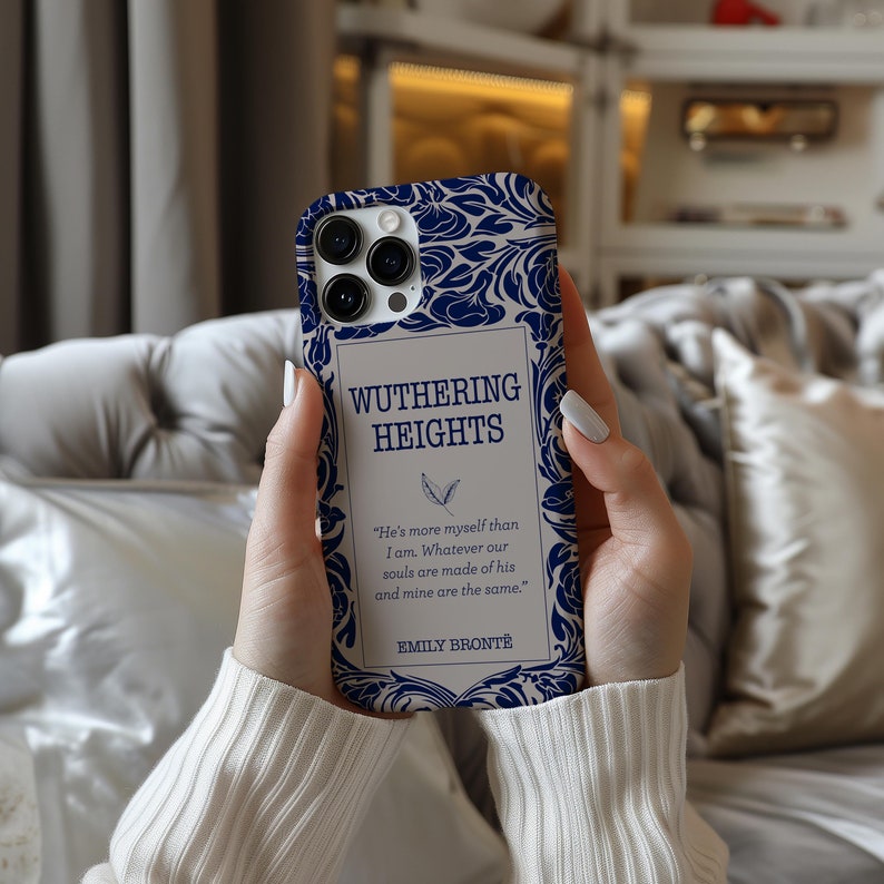 May include: A white and blue phone case with a design inspired by the book "Wuthering Heights" by Emily Bront&euml;. The case features a quote from the book: "He's more myself than I am. Whatever our souls are made of his and mine are the same."