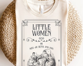 May include: A beige t-shirt with a vintage book cover design featuring the text "Little Women" and "Meg, Jo, Beth and Amy". The design is in black and white and includes an illustration of three girls sitting in a room.