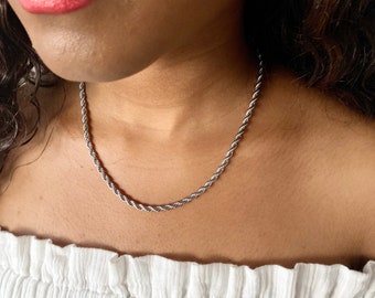 May include: A silver rope chain necklace on a person wearing a white off-the-shoulder top.