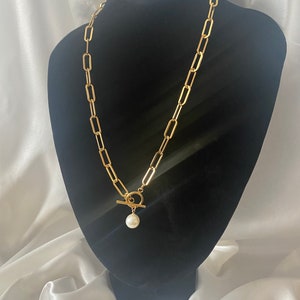 Op de afbeelding: Een gouden ketting met een toggle sluiting en een parel hanger.