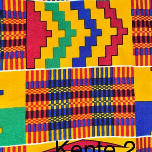 Puede incluir: Un primer plano de una tela colorida con un patr&oacute;n geom&eacute;trico en tonos de amarillo, rojo, verde y azul. La tela tiene una textura tejida y se conoce como tela Kente. El texto "Kente 2" es visible en la parte inferior de la imagen.