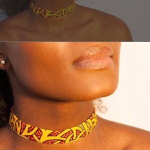 Puede incluir: Un collar gargantilla de tela con estampado amarillo y rojo. La gargantilla est&aacute; hecha de un material suave y flexible y tiene un dise&ntilde;o simple y elegante.