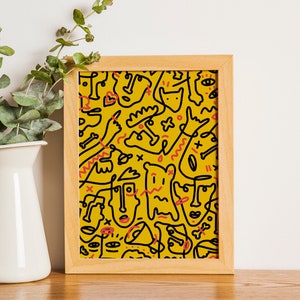 May include: A framed print with a yellow background and black line drawings of abstract faces and shapes. The print is in a wooden frame.