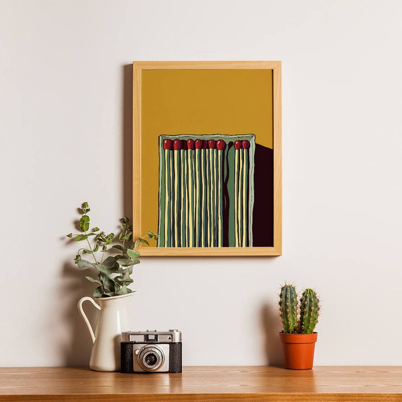 May include: A framed print of a minimalist illustration of a box of matches with red match heads. The background is a solid yellow color.
