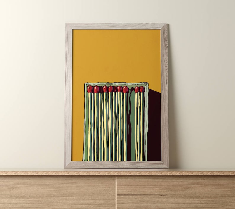May include: A framed illustration of a box of matches with red tips on a yellow background.