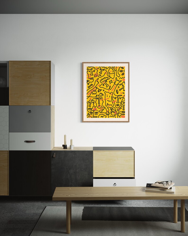 May include: A framed print of a yellow and black abstract design with red accents. The design features a variety of shapes and lines, including faces and figures.