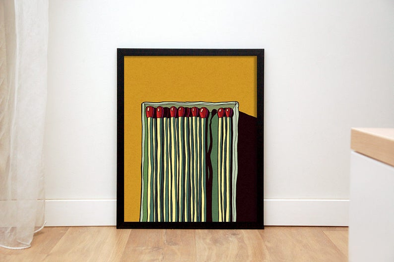 May include: A framed illustration of a box of matches with red tips on a yellow background. The matches are arranged in a vertical row and are surrounded by a black frame.