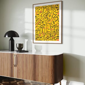 May include: A framed print with a yellow background and black line drawings of faces, figures, and abstract shapes. The artwork has a modern and abstract style.