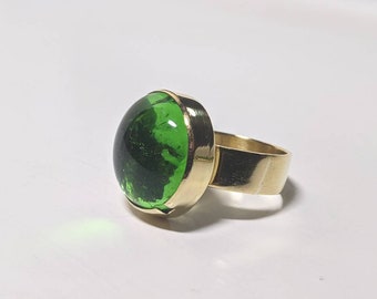 Ronde groene glazen cabochon met messing ring in borstweringstijl:
