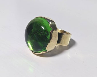 Ronde groene glazen cabochon met messing ring in V-vorm borstweringstijl
