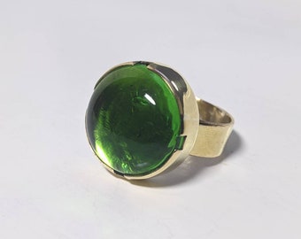 Ronde groene glazen cabochon met messing ring in borstweringstijl: