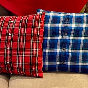 May include: Two decorative pillows made from repurposed plaid shirts. The pillow on the left is red and black plaid, and the pillow on the right is blue and white plaid.