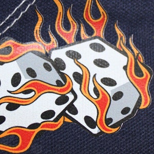 May include: A pair of white dice with black dots are set against a dark blue background. The dice are surrounded by orange and red flames.