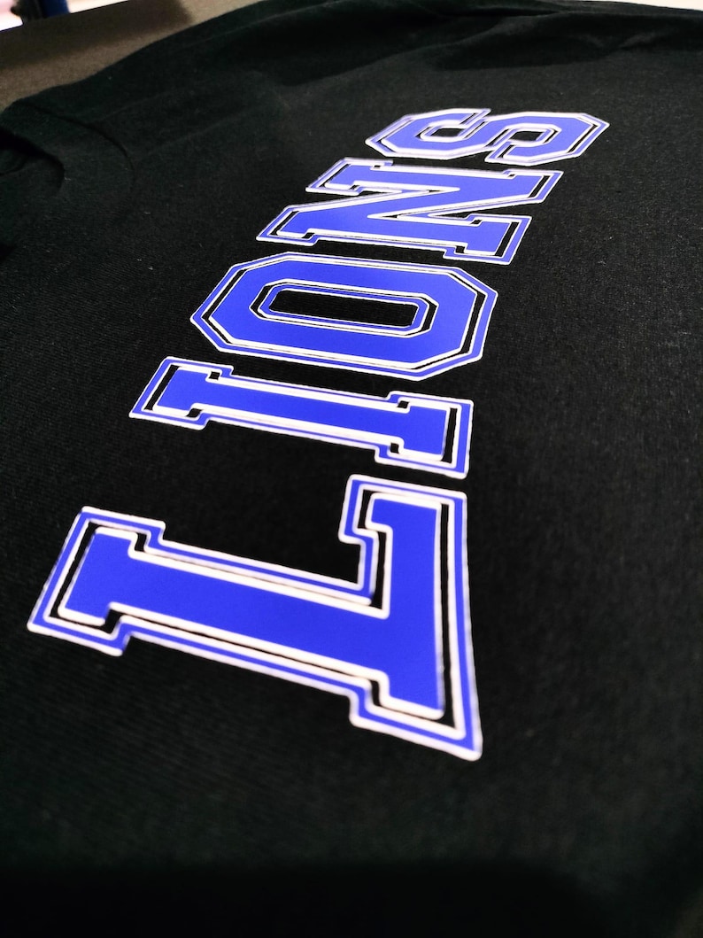 Puede incluir: Una camiseta negra con la palabra "LONG" impresa en letras azules y blancas.