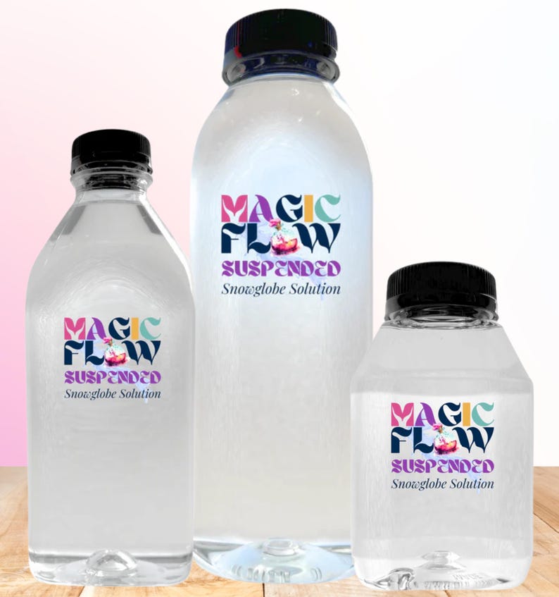 May include: Three clear plastic bottles with black caps, each labeled "MAGIC FLOW Suspended Snowglobe Solution." The labels feature colorful text and a small graphic. The bottles vary in size, with the largest in the center.