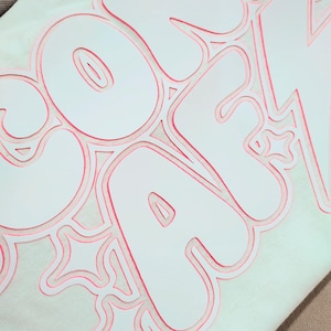 Puede incluir: Sudadera blanca con un contorno rosa de la palabra "COMFY" en una fuente de dibujos animados.