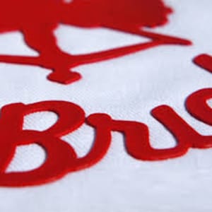 Puede incluir: Letras de vinilo rojo que deletrean "Bride" con una silueta roja de una novia y un novio en el fondo.