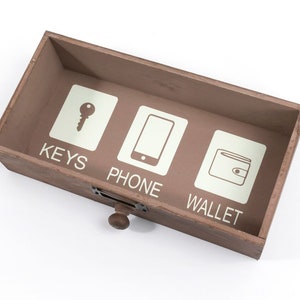 May include: A wooden box with three compartments labeled "KEYS", "PHONE", and "WALLET". Each compartment has a simple icon representing the label.