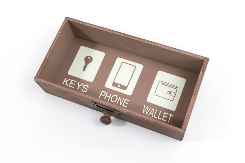 May include: A wooden box with three compartments labeled "KEYS", "PHONE", and "WALLET". Each compartment has a simple icon representing the label.