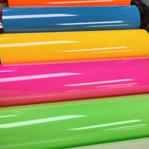Op de afbeelding: Zes rollen vinyl-plakfolie in verschillende kleuren, waaronder oranje, blauw, geel, roze, groen en wit.
