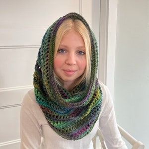 May include: A green, purple, and brown crocheted cowl with a hood. The cowl is made with a variety of stitches and has a lacy pattern.