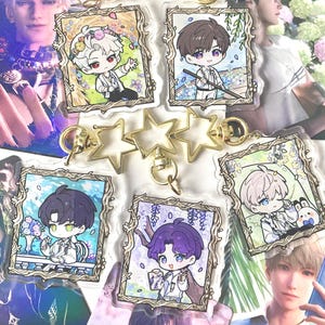 Peut inclure: Plusieurs porte-clés de personnages de style anime et des porte-clés dorés en forme d'étoile. Les porte-clés présentent des illustrations encadrées de divers personnages. L'arrière-plan comprend des impressions d'art de personnages avec des thèmes floraux et fantastiques.
