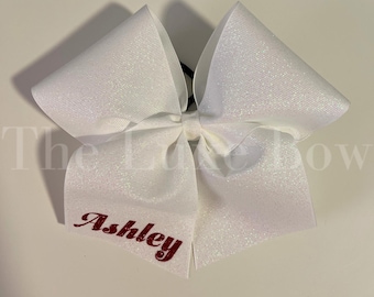 Puede incluir: Lazo para el pelo blanco con purpurina con el nombre "Ashley" escrito en granate.