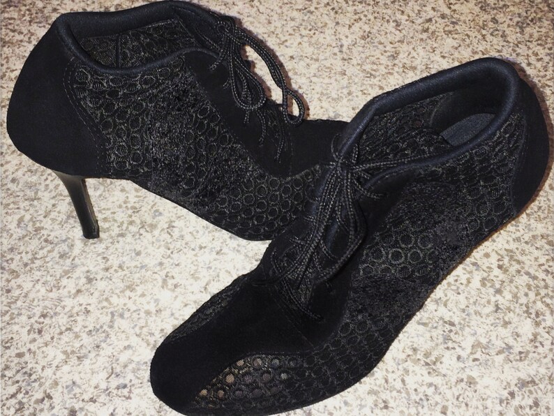 May include: A pair of black heeled ankle boots with lace-up fronts and a delicate patterned design.