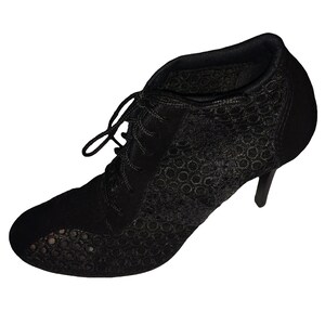 May include: Black lace ankle boots with a high heel. The boots have a lace-up front and a pointed toe.