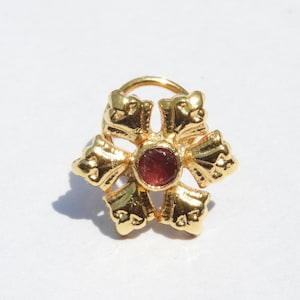 May include: Gold nose ring with a red gemstone in the centre, shaped like a flower with six petals.