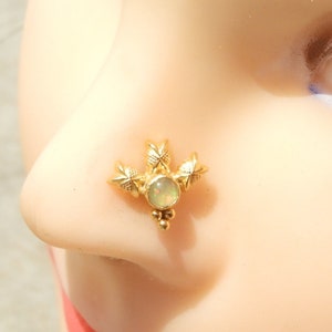 Könnte beinhalten: Goldener Nasenring mit einem weißen Opal-Stein und drei blattförmigen Akzenten.