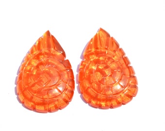May include: A pair of orange, carved, teardrop-shaped earrings. The earrings have a spiral design.