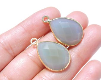 May include: Two gray gemstone teardrop pendants with gold-toned metal settings. The pendants are faceted and have a smooth, polished finish.