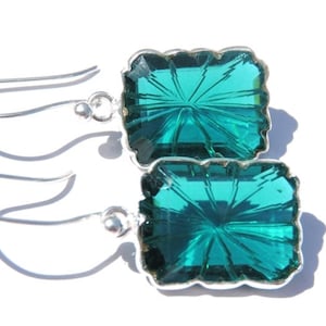 Puede incluir: Un par de pendientes de plata con piedras cuadradas facetadas de color verde azulado.