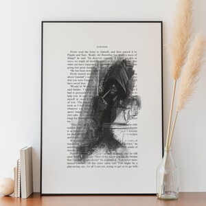 May include: A framed art print featuring a black and white illustration of a hooded figure smoking a pipe, overlaid on a page of printed text titled STRIDER. The artwork is displayed in a thin black frame with a white matting border.