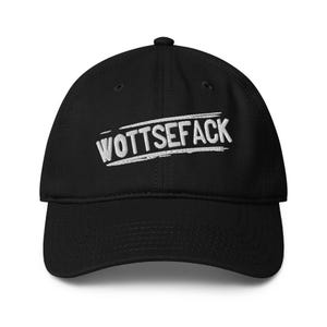 May include: Black baseball cap featuring the embroidered word "WOTTSEFACK" in white. The text is in a bold, stylized font and is slightly angled across the front of the cap. The cap has a curved peak and a button on top.