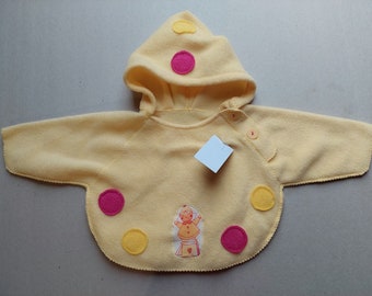 以下が含まれることがあります： ピンクと黄色の水玉模様と、子供を刺繍した小さな画像がついた、黄色のフード付きフリースのベビーセーターです。