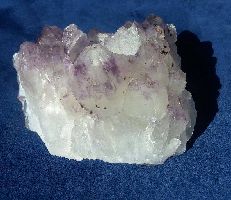 May include: A large, clear quartz crystal cluster with purple amethyst crystals embedded throughout. The cluster has a natural, rough texture and is a beautiful example of a natural crystal formation.