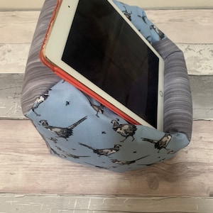 Könnte beinhalten: Ein blauer und grauer Tablet-Ständer aus Stoff mit einem Fasanen-Druck. Der Ständer ist schräg aufgestellt, mit einem Tablet darauf.
