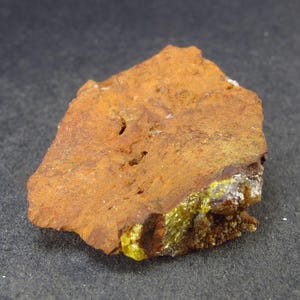 May include: A rough, orange-brown rock with a patch of bright yellow mineral crystals.